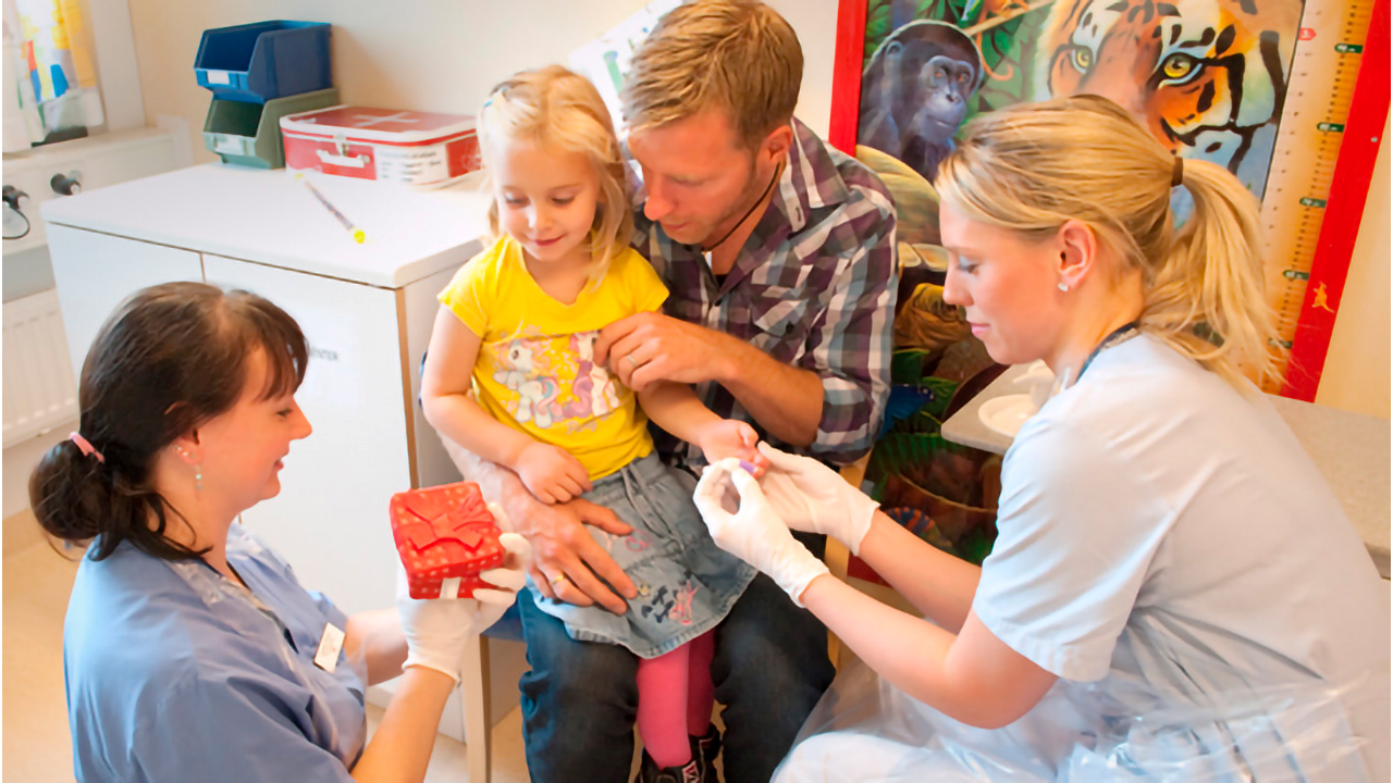 Emelie som är sjuksköterska tar provet i fingret.