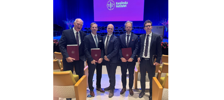 fem män i kostym i aula framför lila skärm med logga och text Karolinska Institutet
